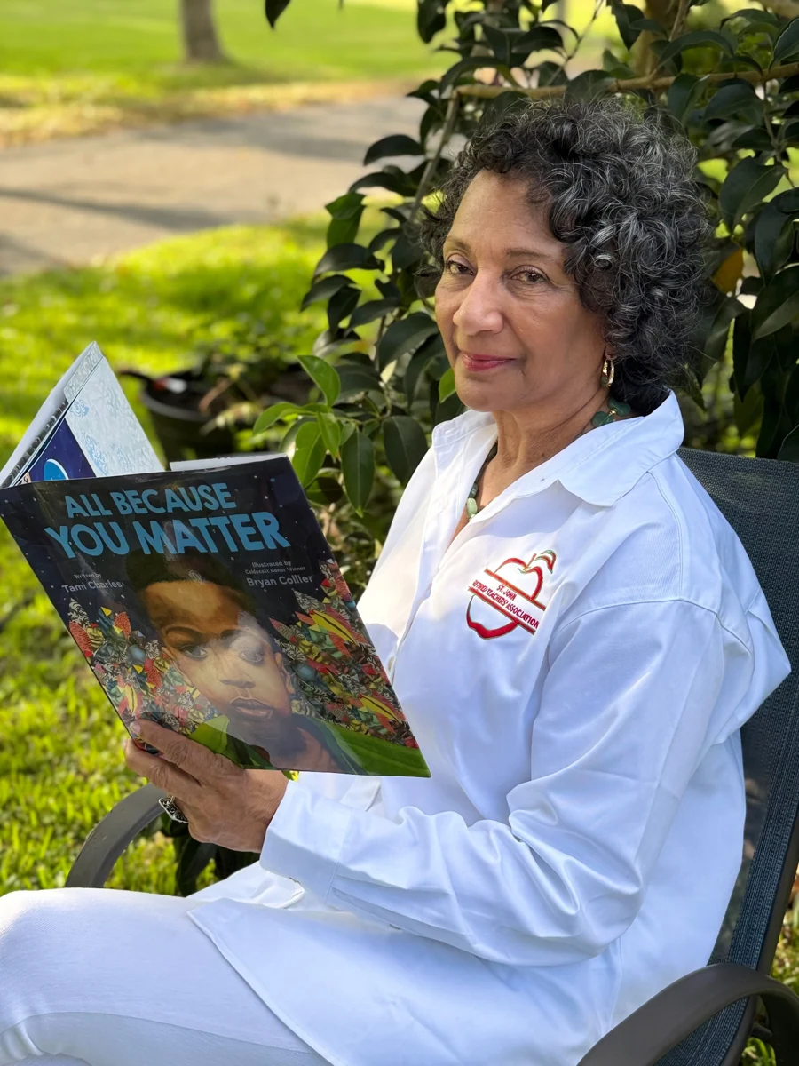 Stephenie Aubert seated outdoors reading a children's book